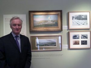 Lord Ashton standing by paintings in Indian hospital gallery