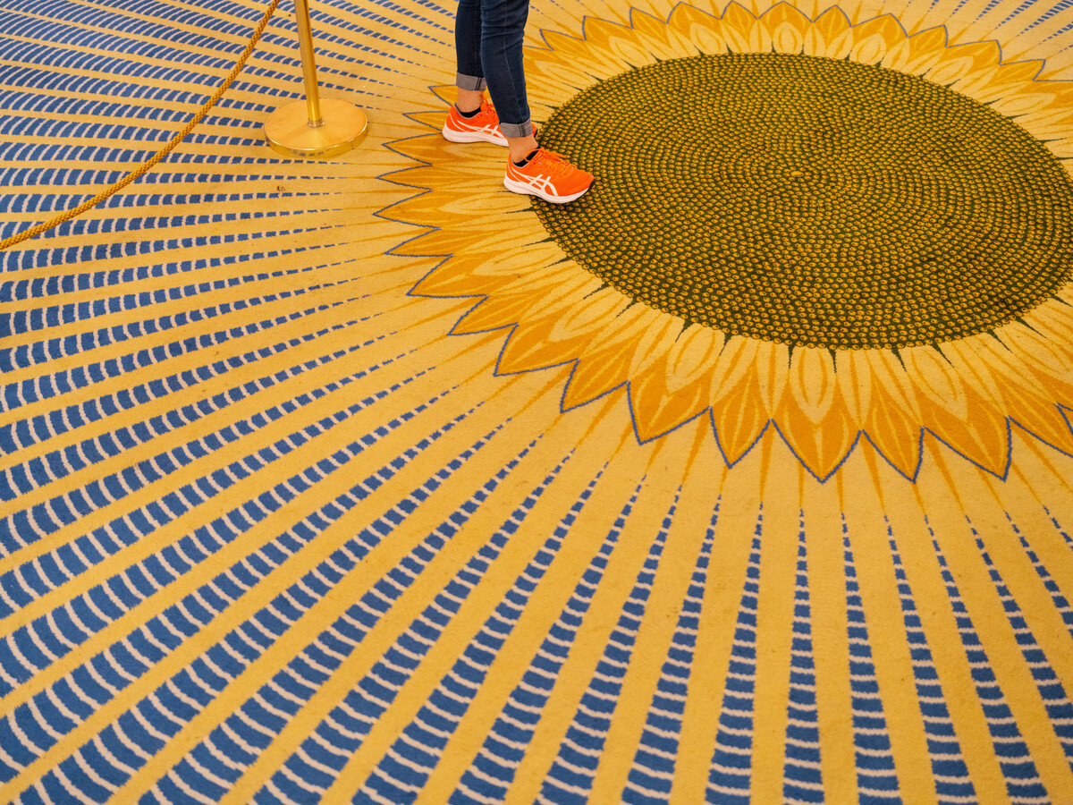 Foot on carpet bearing image of sunflower.