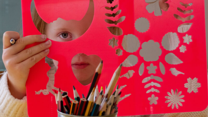 Young child looking through a plastic stencil.