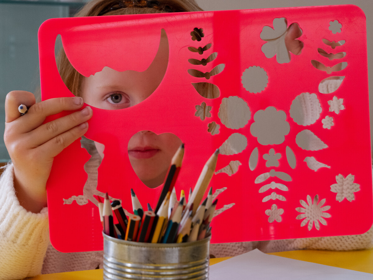 Young child looking through a plastic stencil.