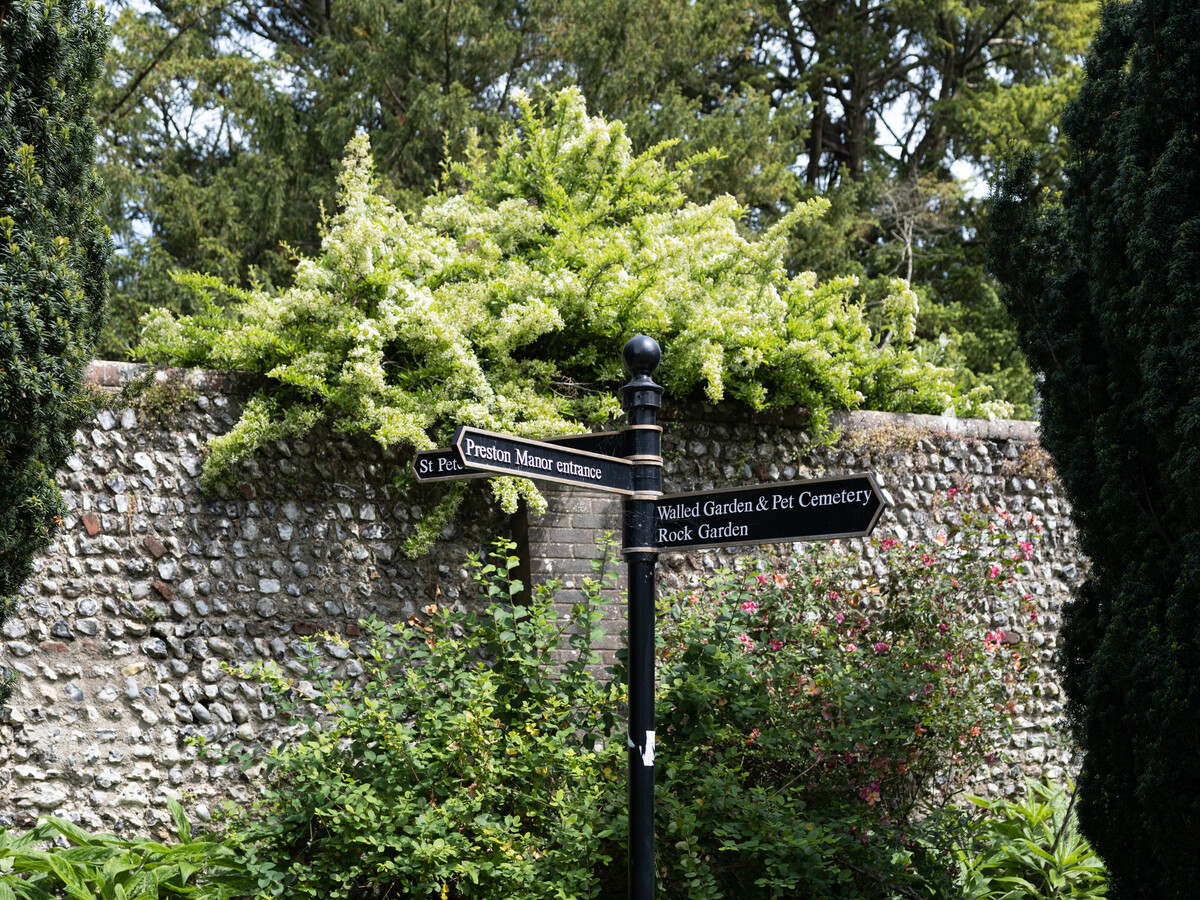 Sign post in front of flint cobble wall.