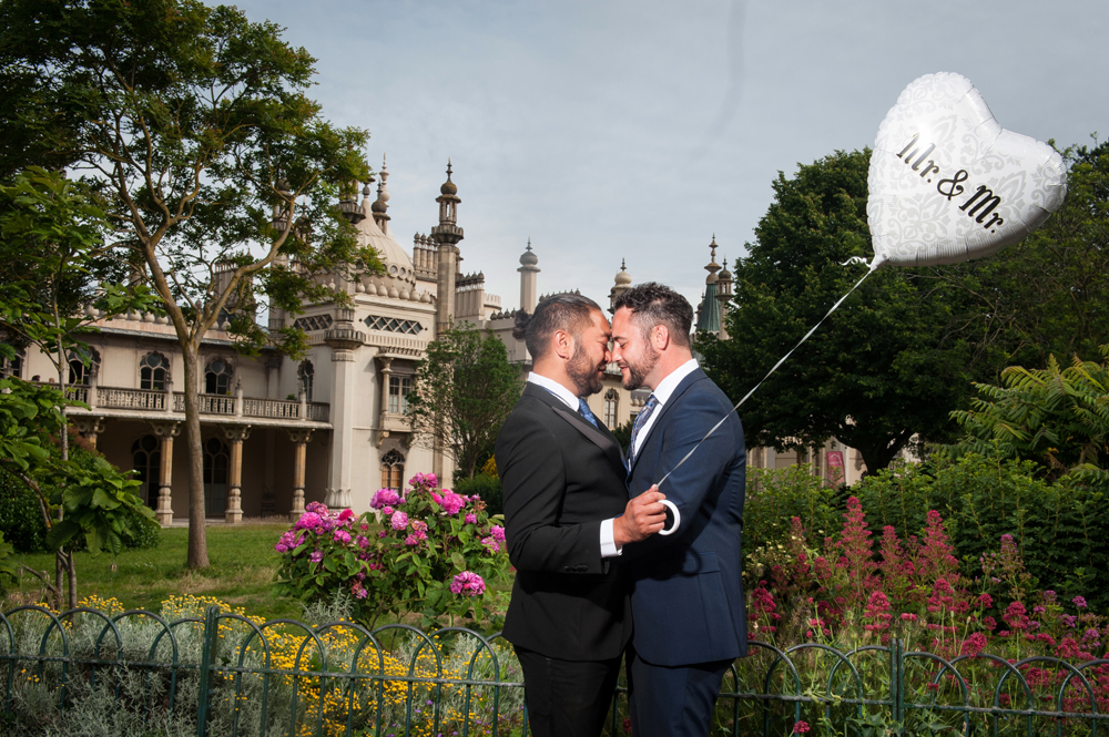 Two grooms embracing in Royal Pavilion Garden.