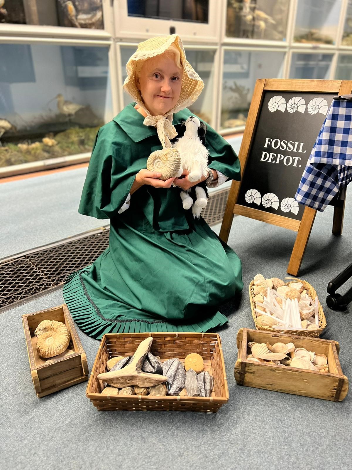 A woman dressed as Mary Anning poses with fossils at the Booth Museum.