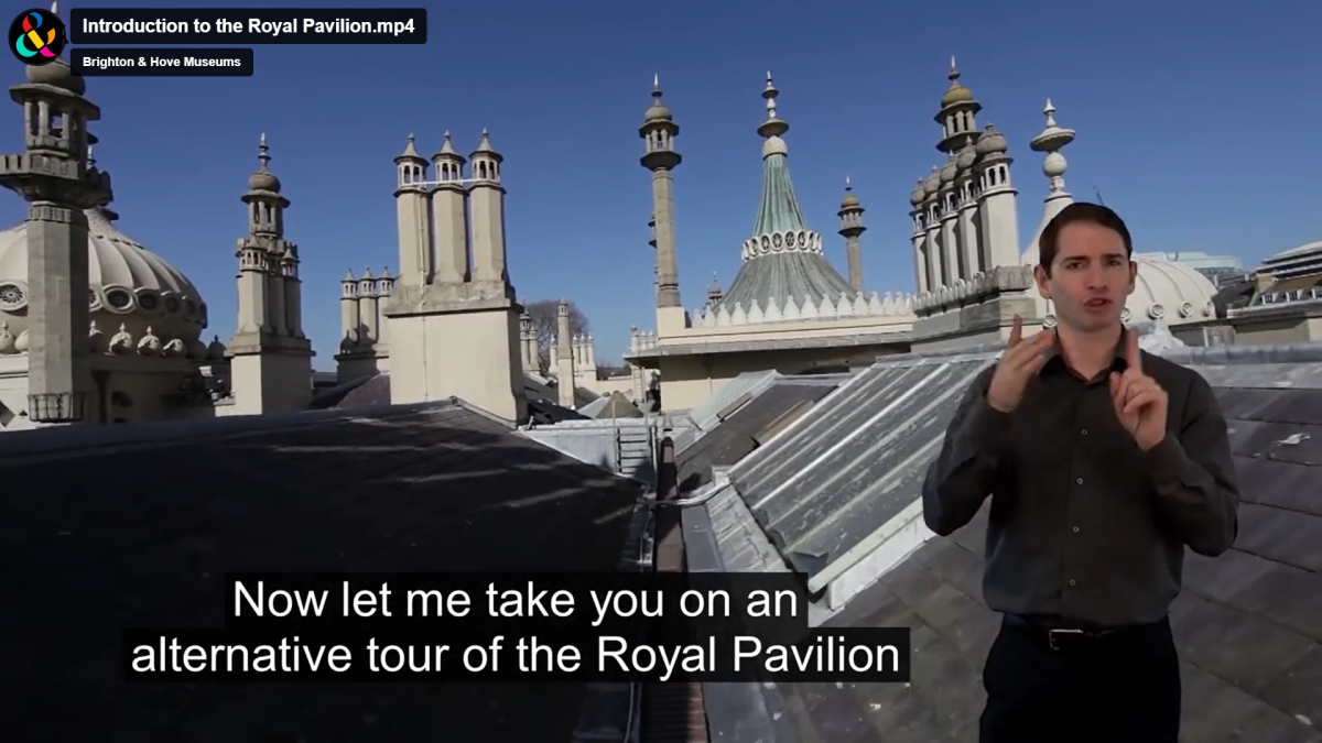 Still from video showing the roof of the Royal Pavilion, alongside a BSL interpreter and a subtitle.