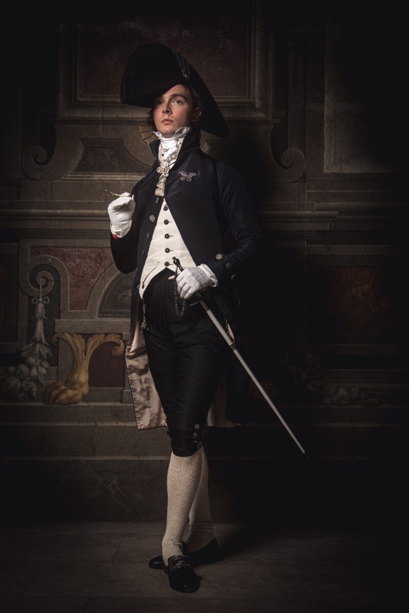 A man dressed in Regency clothing with a dark background.