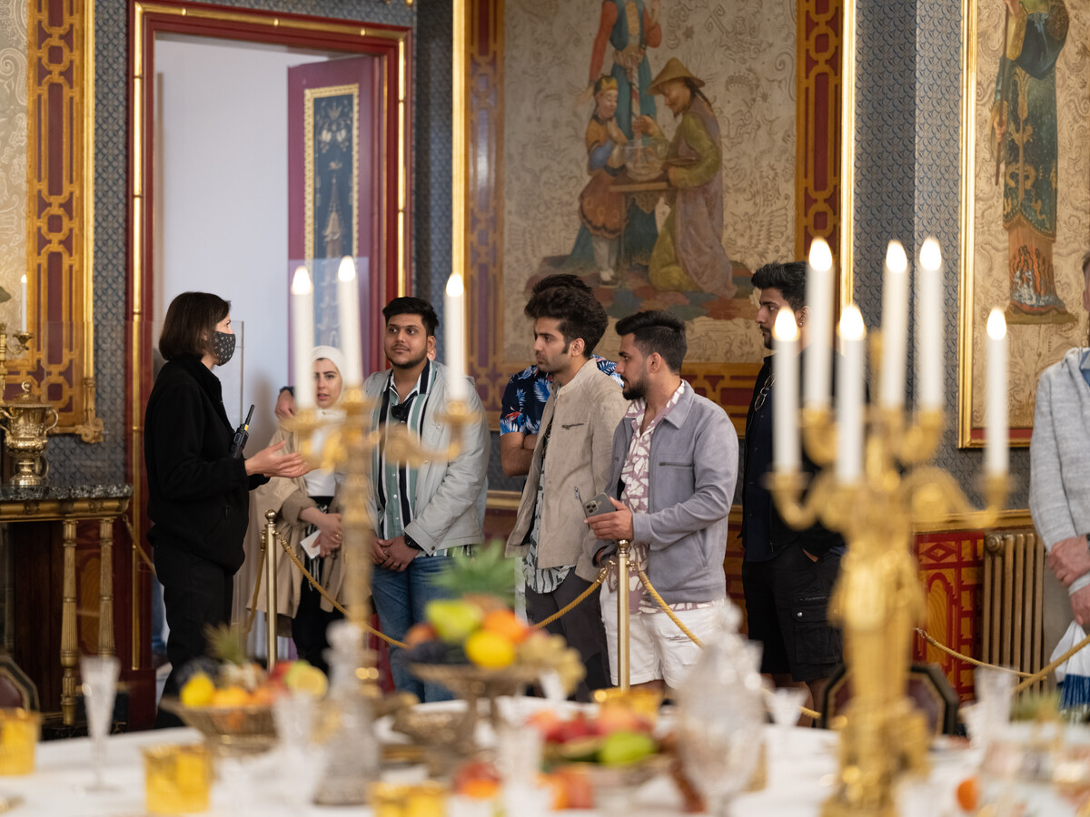 A Royal Pavilion Visitor Services Officer explains the features of the Banqueting Room to a group of visitors
