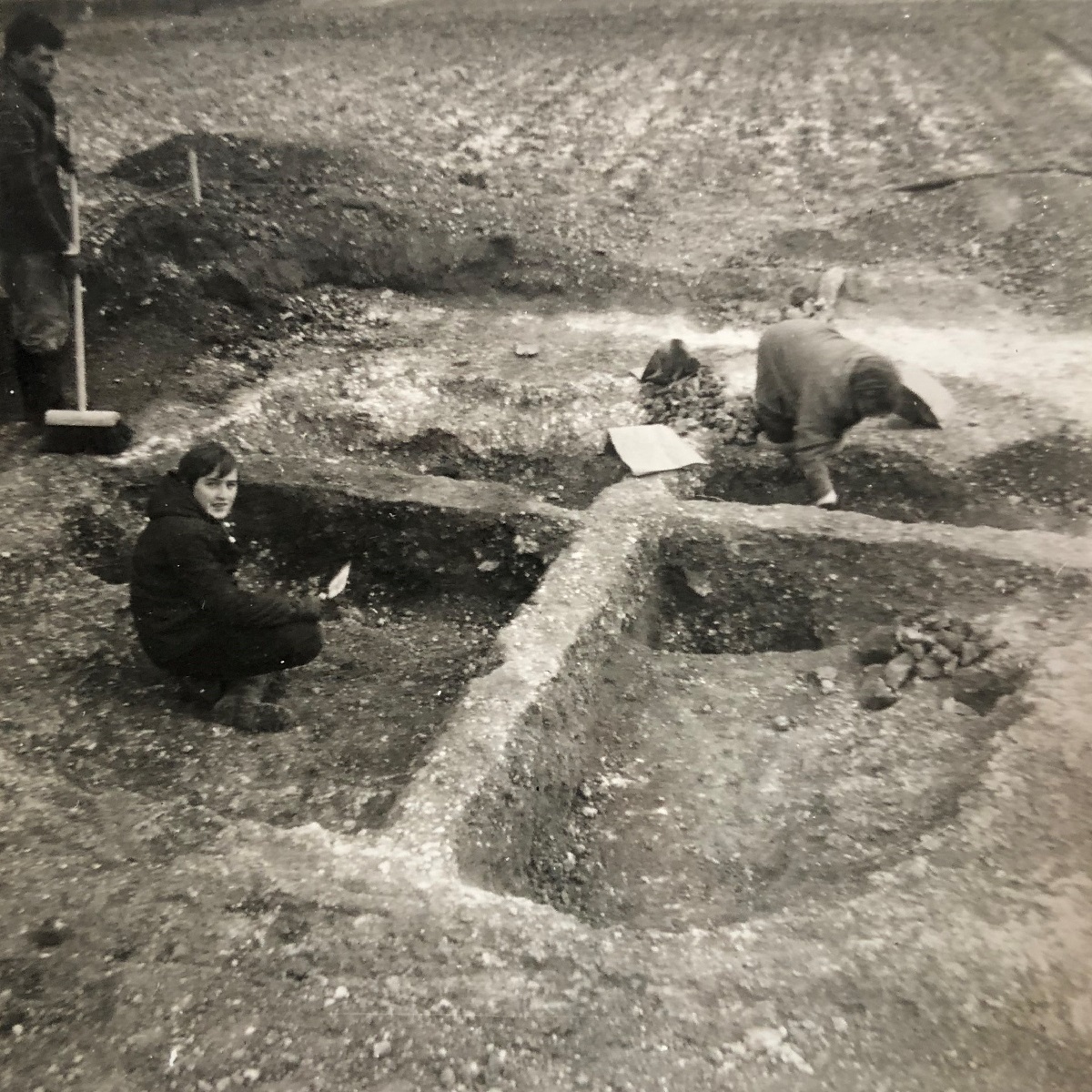Photograph of two people carrying out an archaeological excavation of ‘Hut II’ on the adjacent Anglo-Saxon settlement, 1968