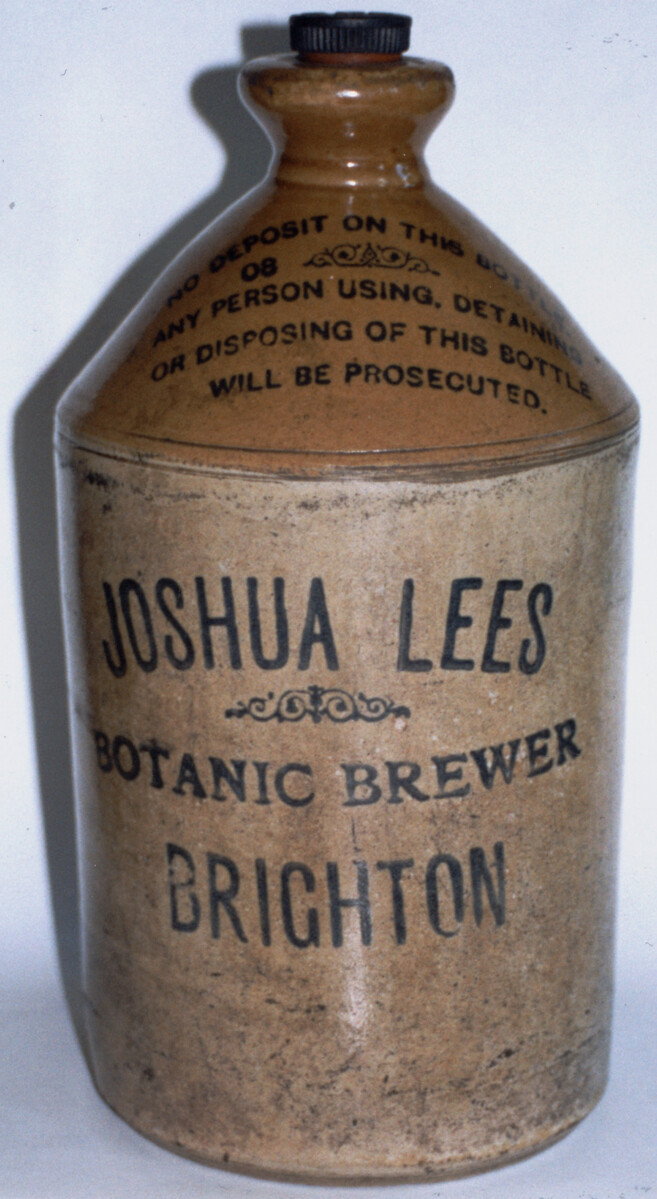 Stoneware ginger beer bottle, glazed brown neck and glazed cream body with handle. Black metal screw top lid, inscribed 'R. Fry and Co Ltd'. Body of bottle inscribed in black 'JOSHUA LEES BOTANIC BREWER, BRIGHTON'.