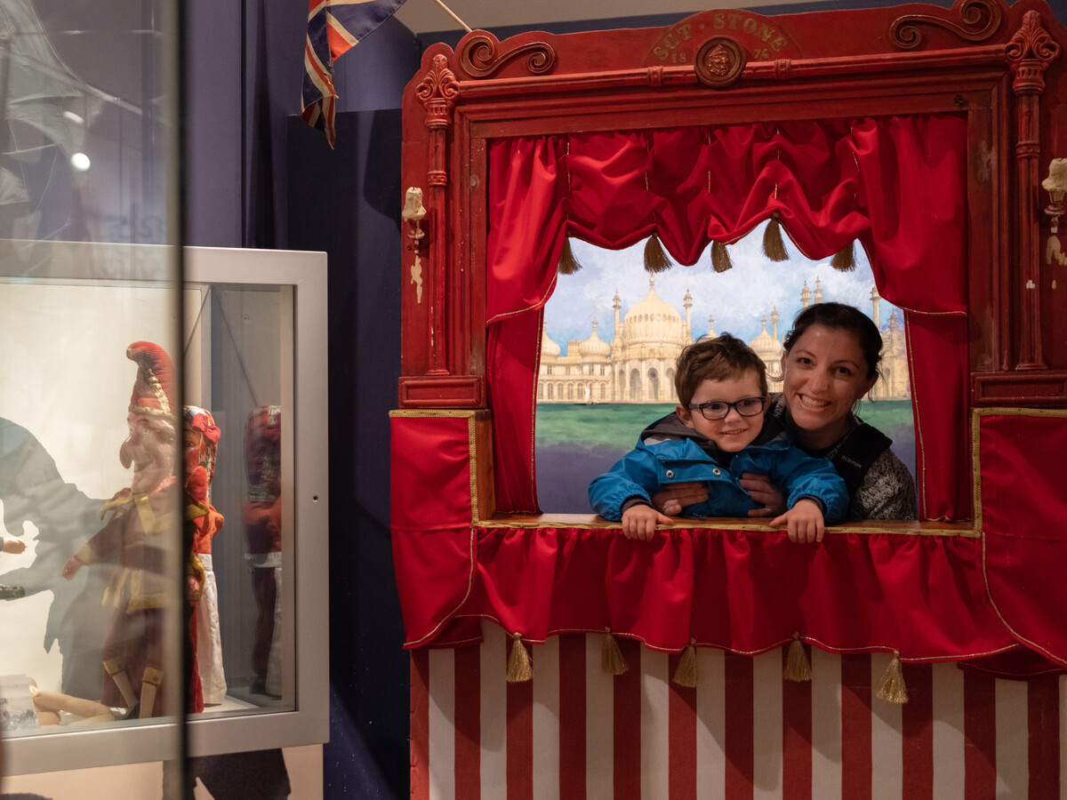 Mother and son in Punch & Judy booth in Performance Gallery of Brighton Museum.