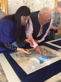 Experts discussing a fragment of silvered Chinese wallpaper from the Prince Regent’s private apartments