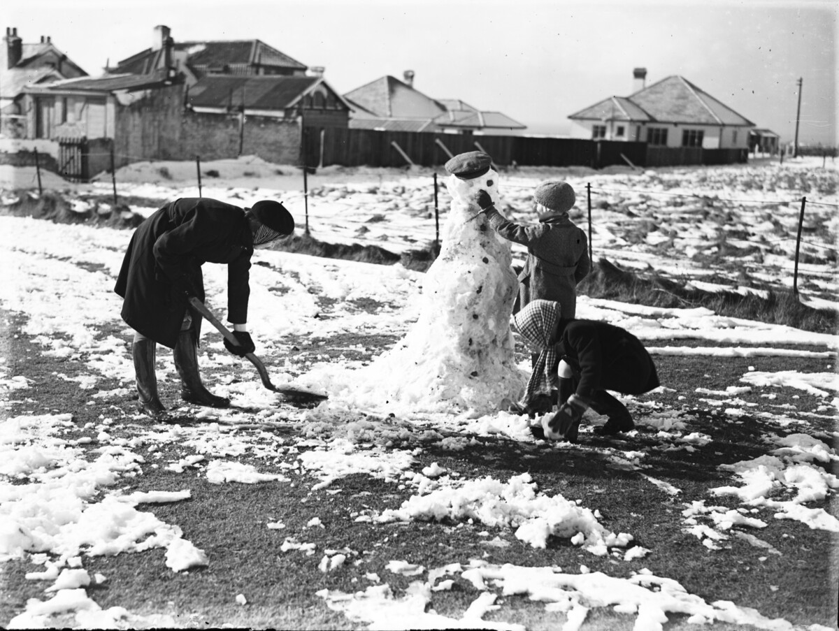 A woman and two children building a snowman in Brighton. 19 February, 1938.