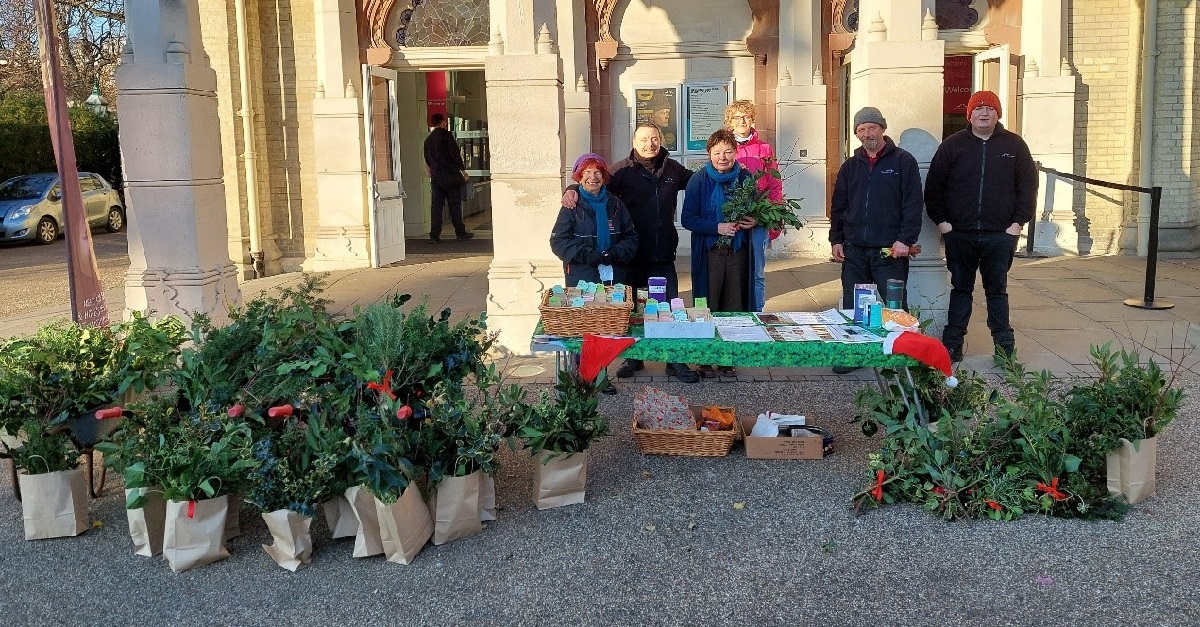 The Royal Pavilion Garden team stand by a table in the Garden, they are selling material from the Garden to make Christmas wreaths