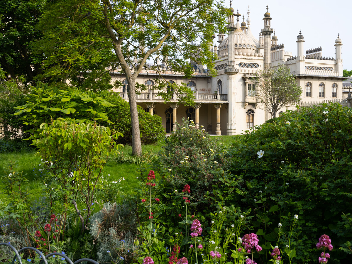 External view of the Royal Pavilion from the Garden. Many plants, flowers and trees are in the foreground