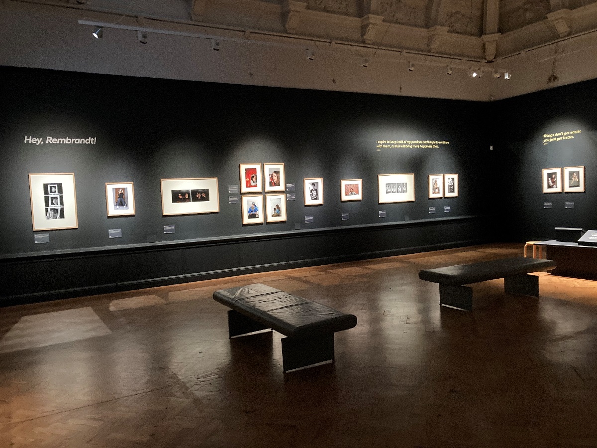 National Treasures Rembrandt in Brighton, gallery image. The photograph shows a wide shot of a dark gallery with photographic portraits along the far wall