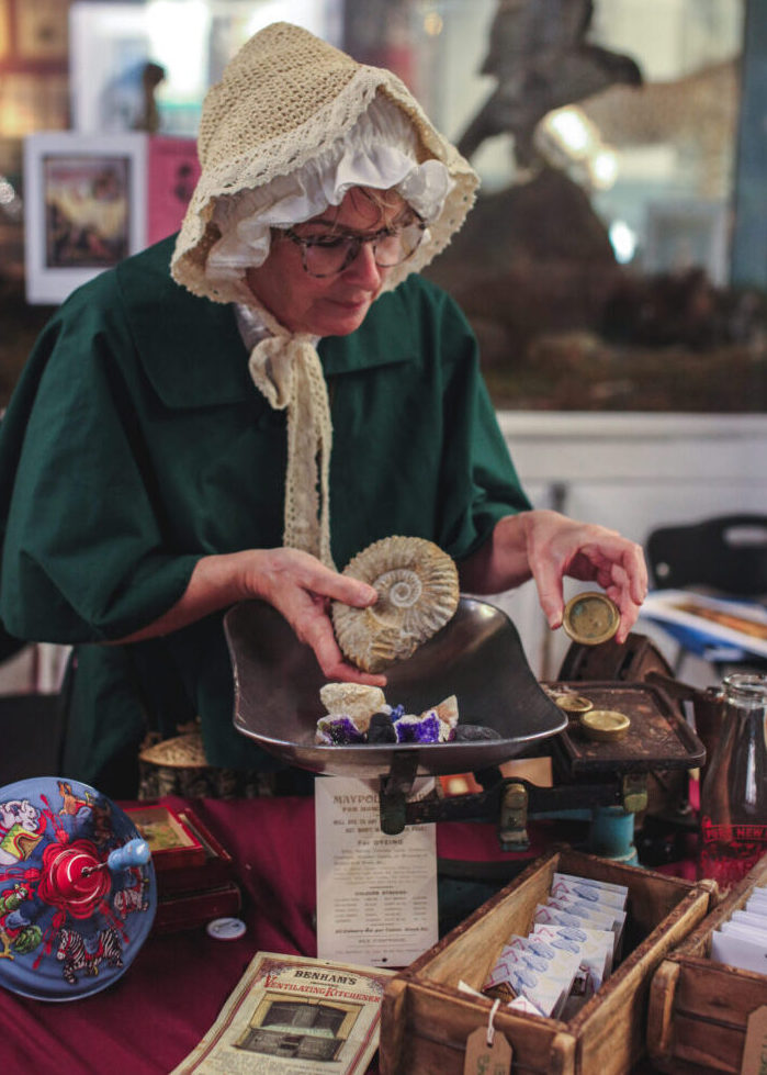 Booth Museum's employee dressed as Mary Anning, is holding fossils in her hand.