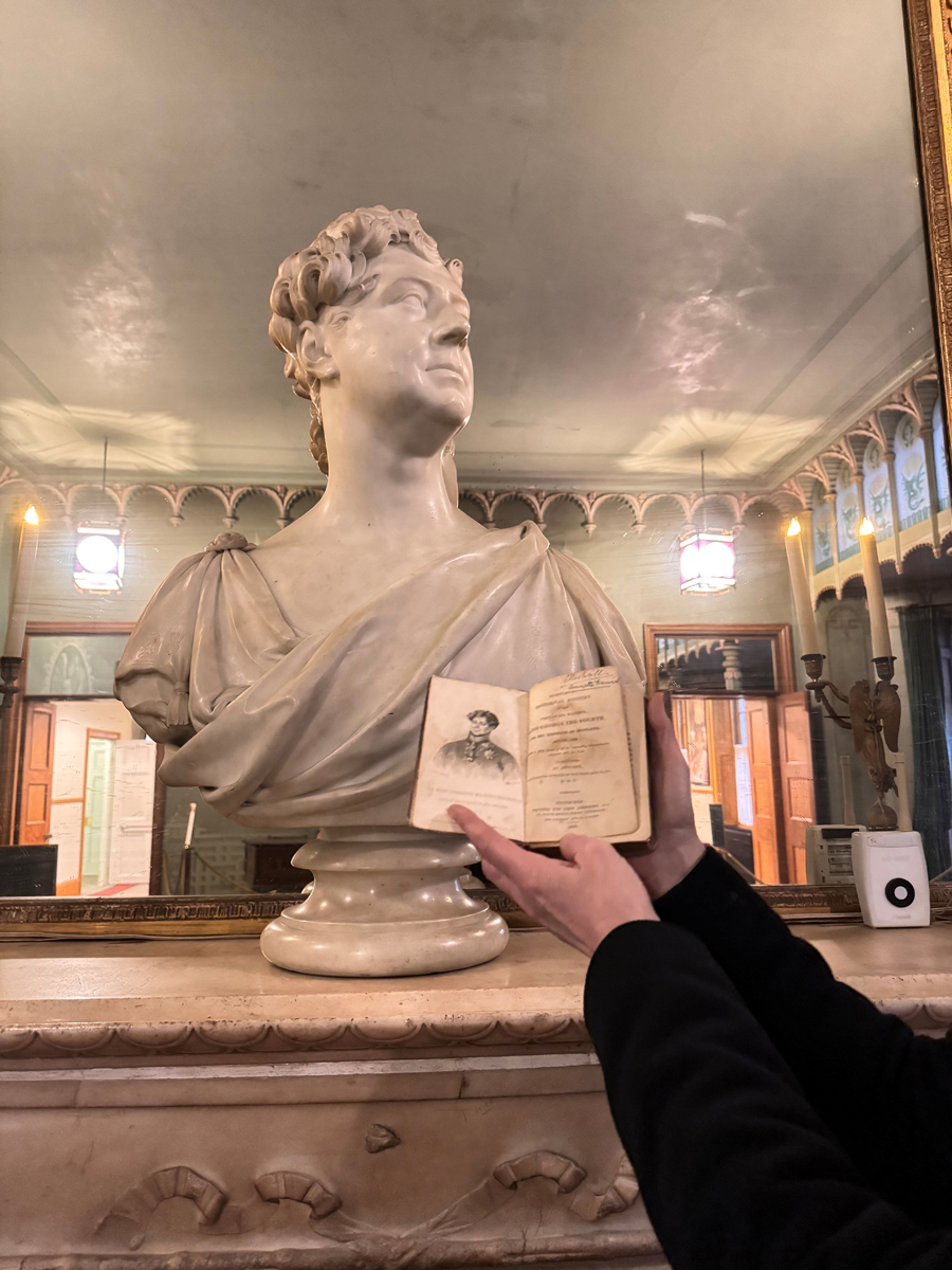 Alexandra holding her copy of An account of George IV visit to Edinburgh August 1822, by a bust of George