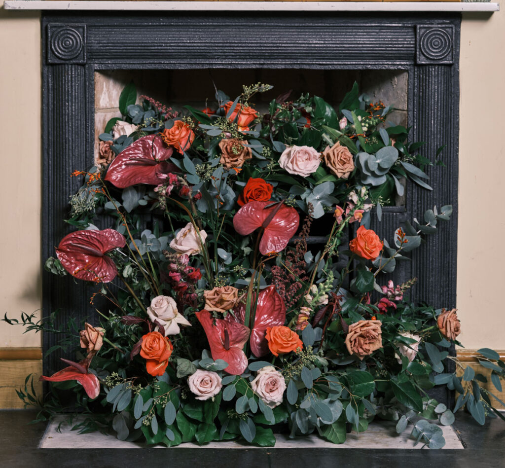 Red Drawing Room foyer flowers in fireplace
