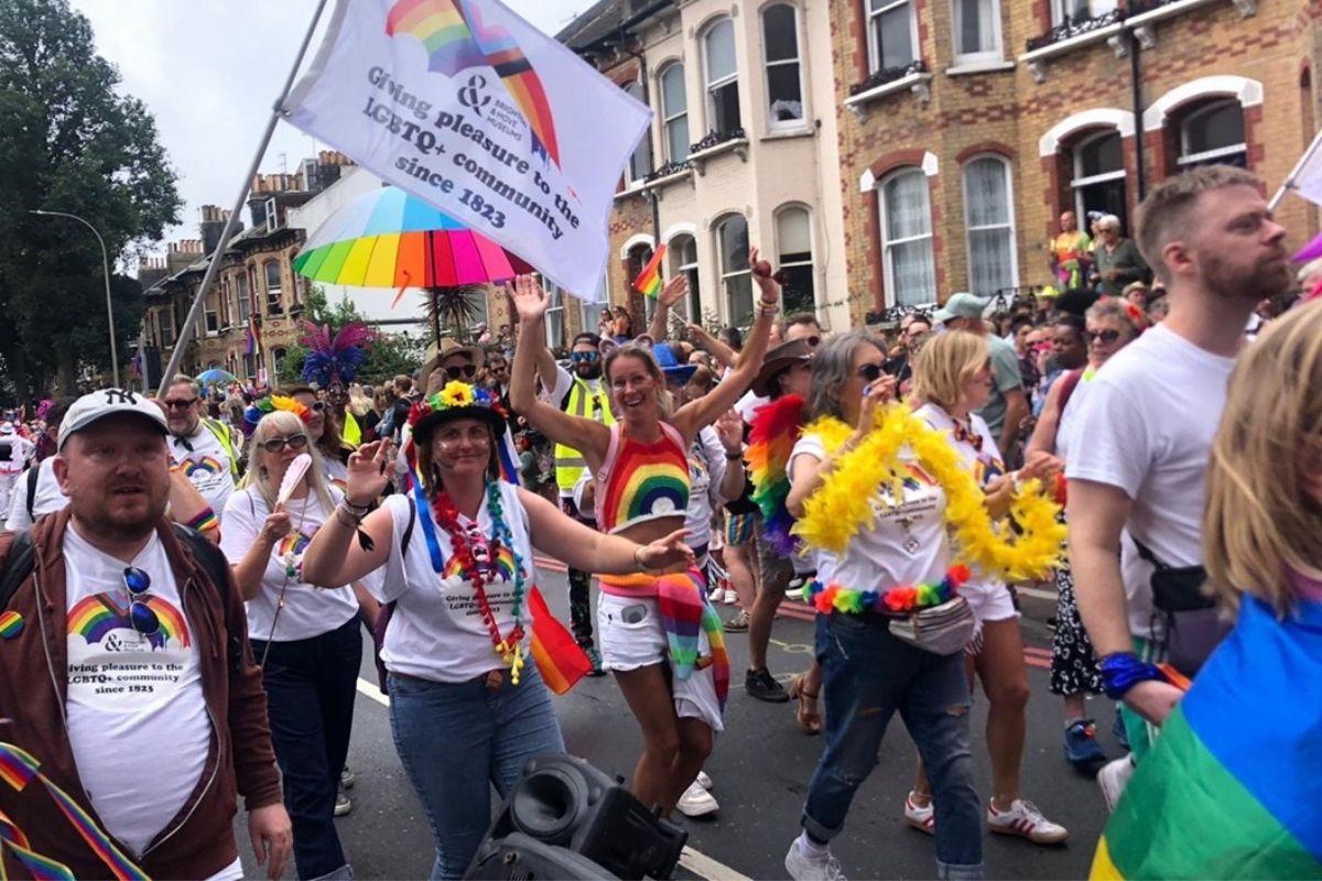 People in the pride parade wearing Brighton & Hove Museum t-shirts and waving flags
