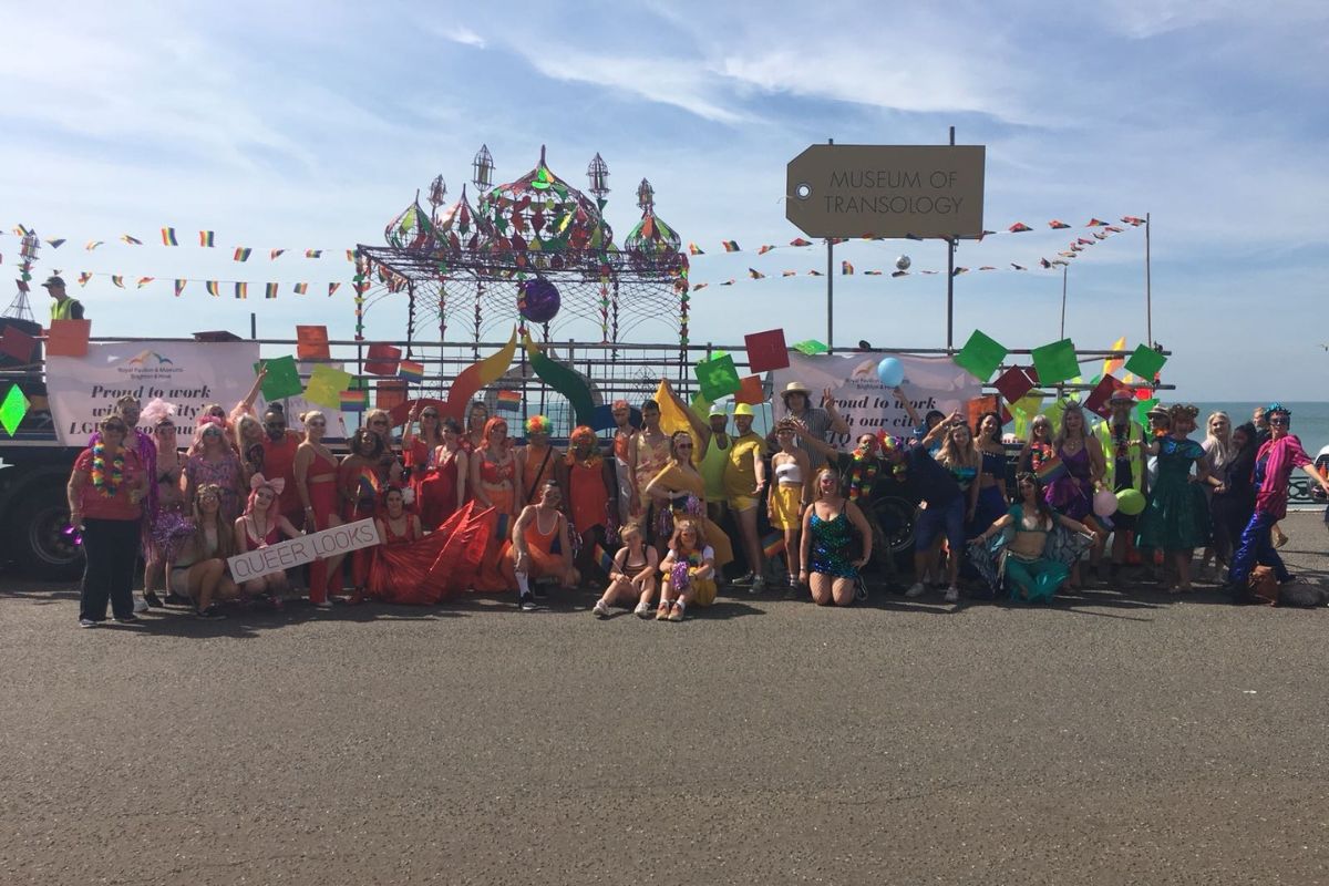 Brighton & Hove Museums group standing in front of a float decorated to look like the Royal Pavilion. Participants are all wearing colourful outfits
