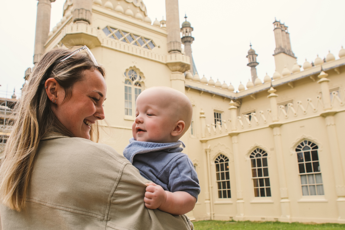 Baby Pavilion promotional image, a mother holds her baby outside the Royal Pavilion