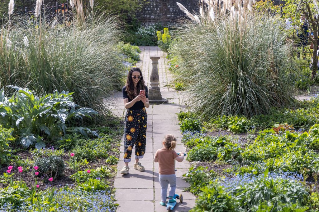 A woman takes a photograph of a child in Preston Manor Gardens