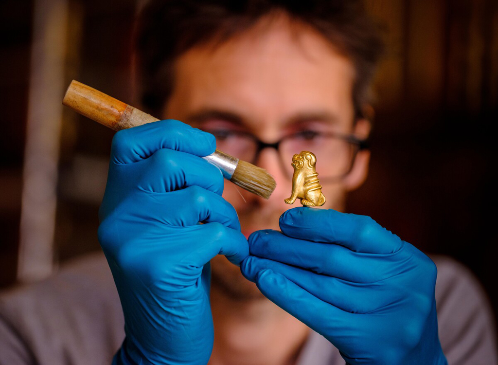 Andy Thackray, Objects Conservator painting gold miniature lion.