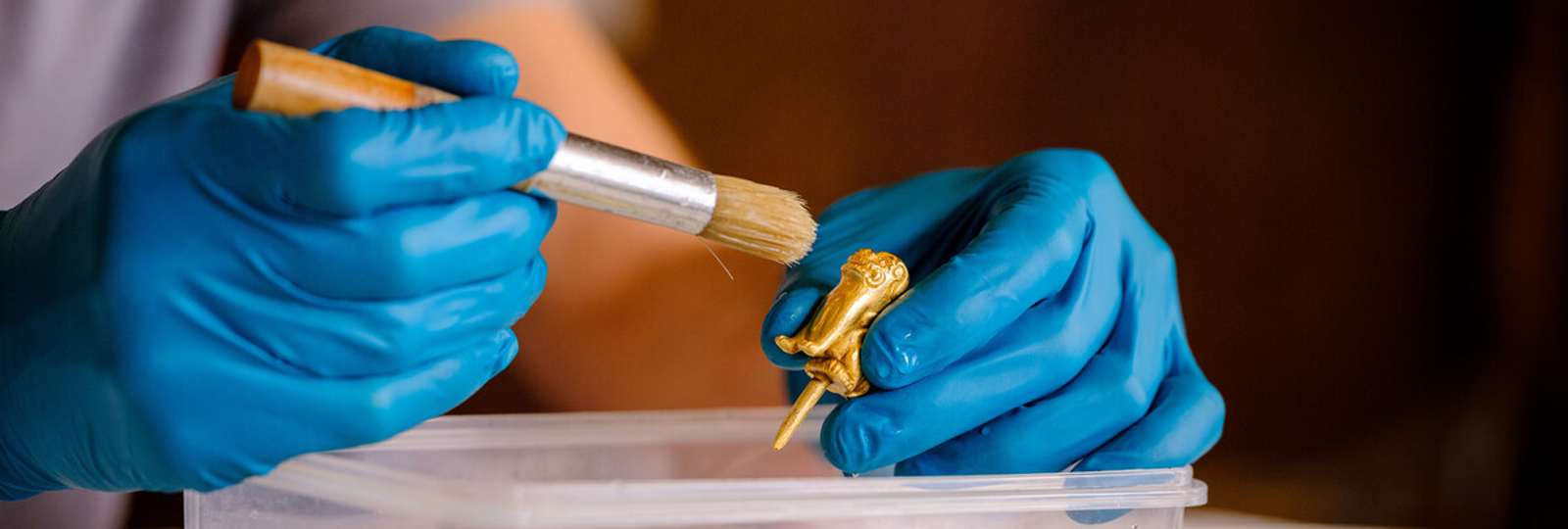 Andy Thackray, Objects Conservator painting gold miniature lion.