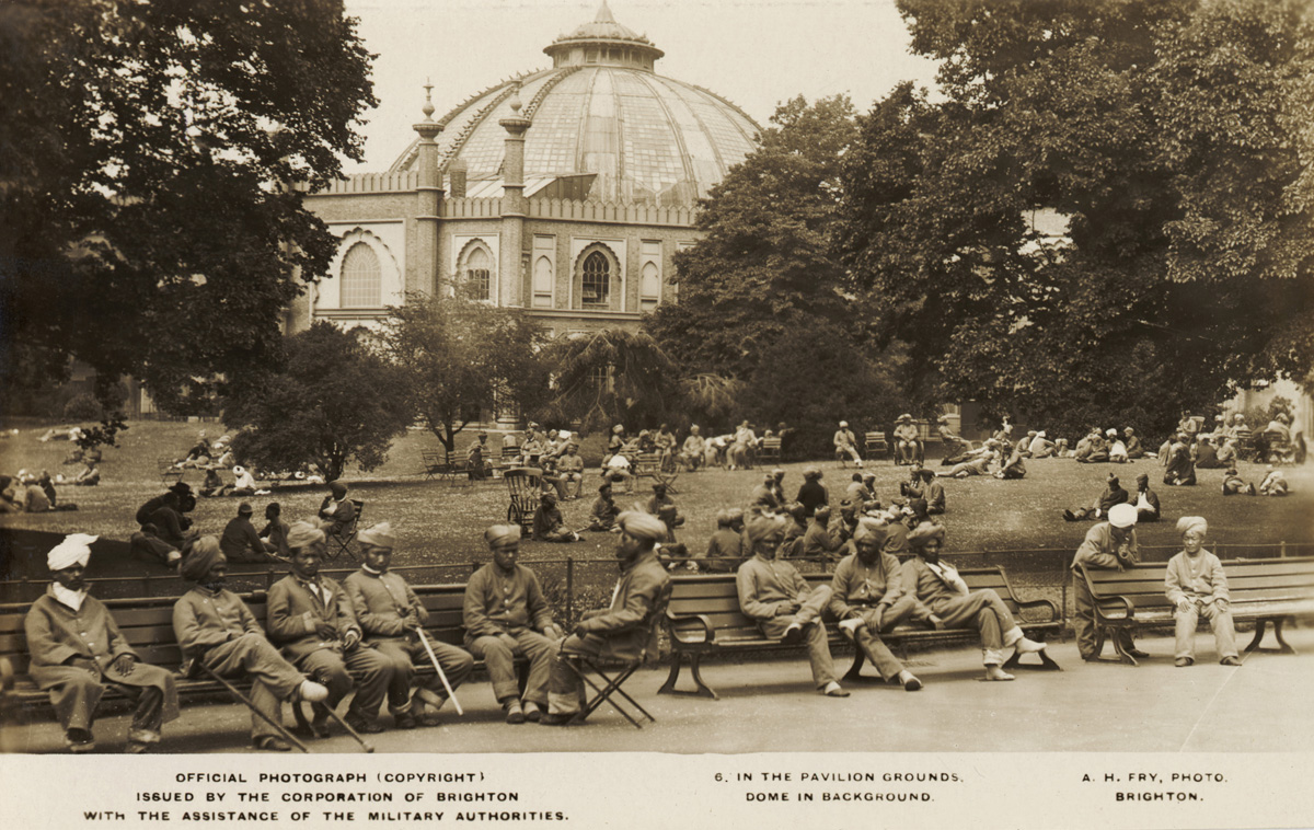 Indian soldiers on the grounds of the Royal Pavilion. Injured soldiers sit on benches or the grass. The Dome can be seen in the background.