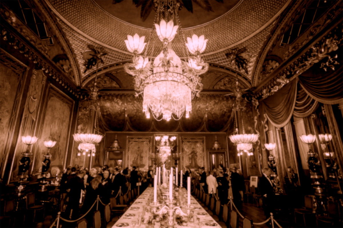 The Banqueting Room of the Royal Pavilion during an event. People in formal wear stand talking around the banqueting table