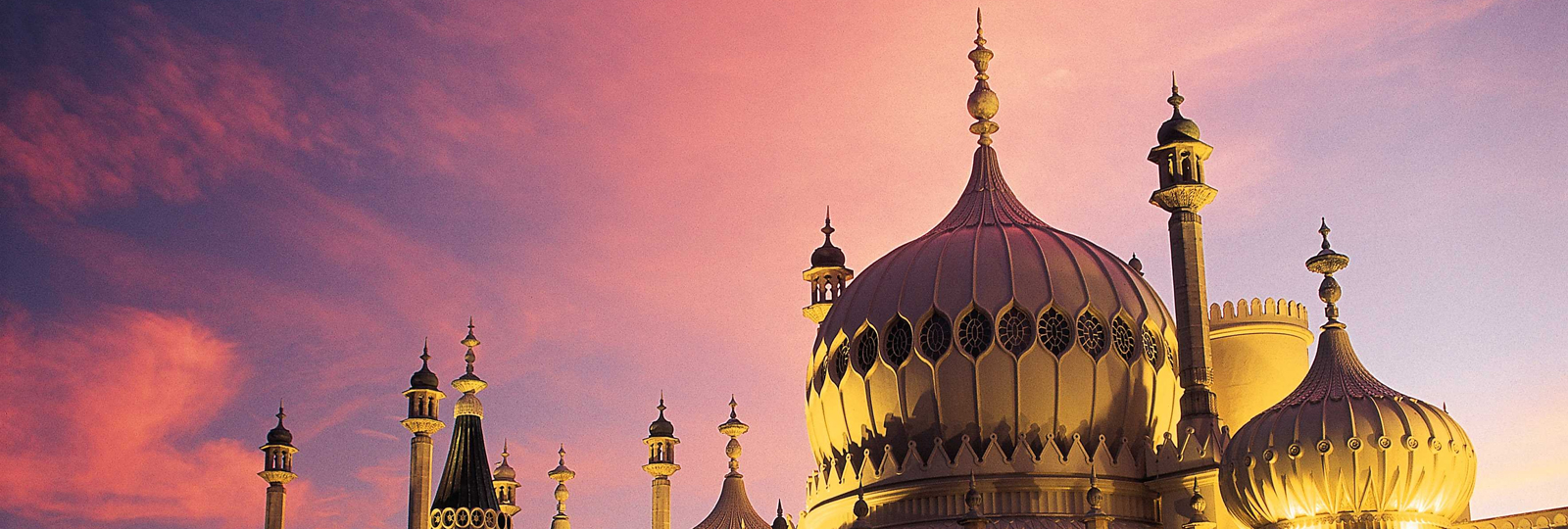 Royal Pavilion at Sunset. East Exterior view against a pink and pale blue sky. The Pavilion is lit by external yellow lightning