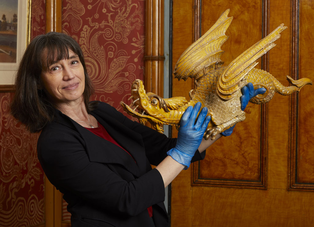 Photograph of Curator Alexandra Loske holding a decorative dragon from the interiors of the Royal Pavilion