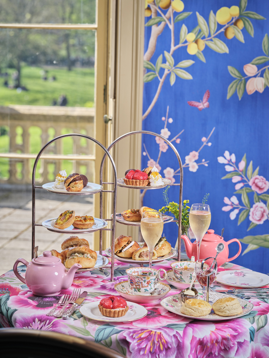 Afternoon tea in the Adelaide Suite of the Royal Pavilion. Two cake stands full of sandwiches, scones and cakes and on the table with pots of tea and glasses of sparkling wine.