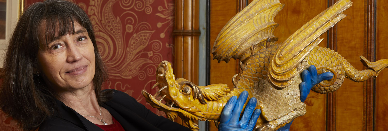 Photograph of Curator Alexandra Loske holding a decorative dragon from the royal pavilion interior