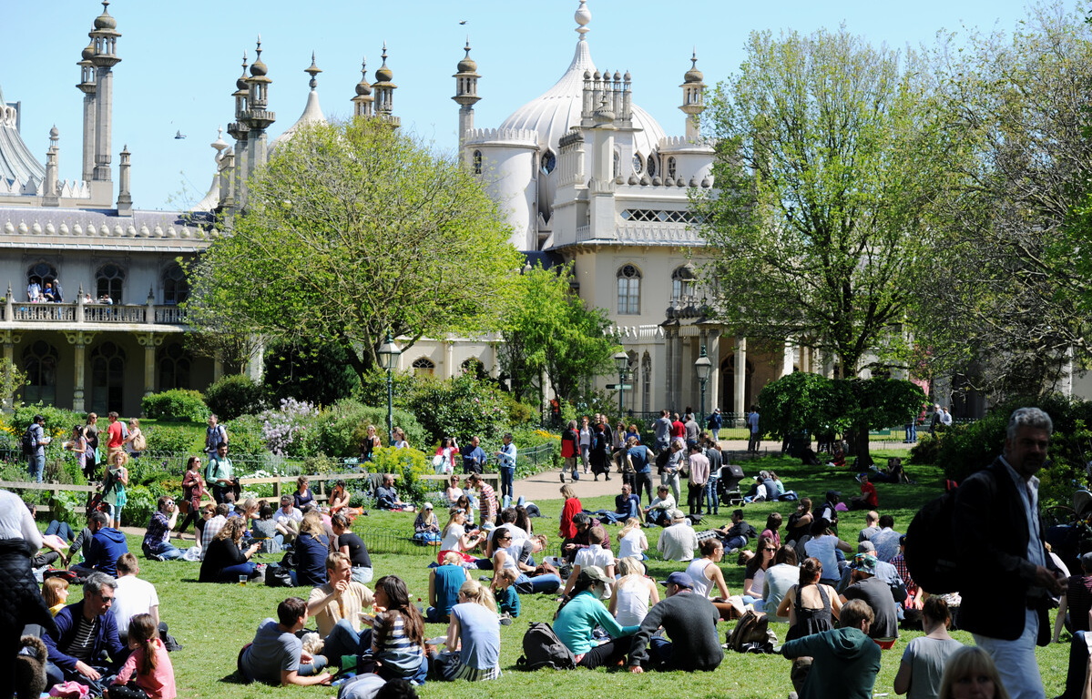Photograph of the Royal Pavilion Garden with lots of people sitting on the lawn