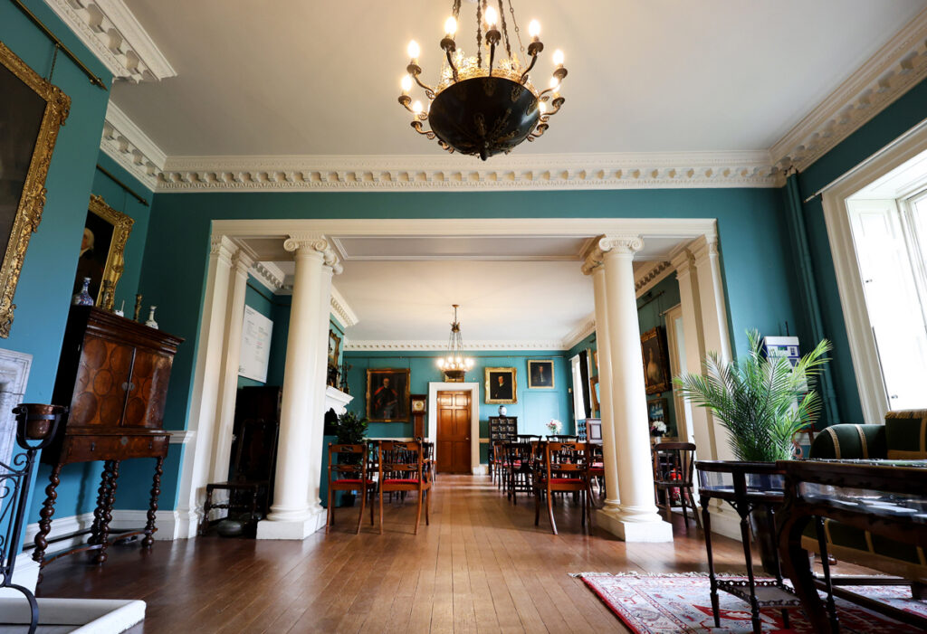 Preston Manor entry hall set for a wedding. The floorspace of the room has been cleared to allow for rows of wooden chairs with red velvet cushions.