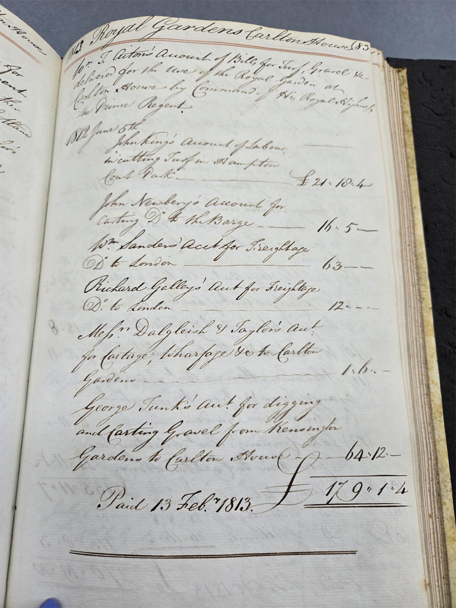 Extract from Lord Chamberlains Accounts. A large aged book with white pages is open to display a page of black handwritten accounts. The end of which writes "Paid 13. Feb 1813"