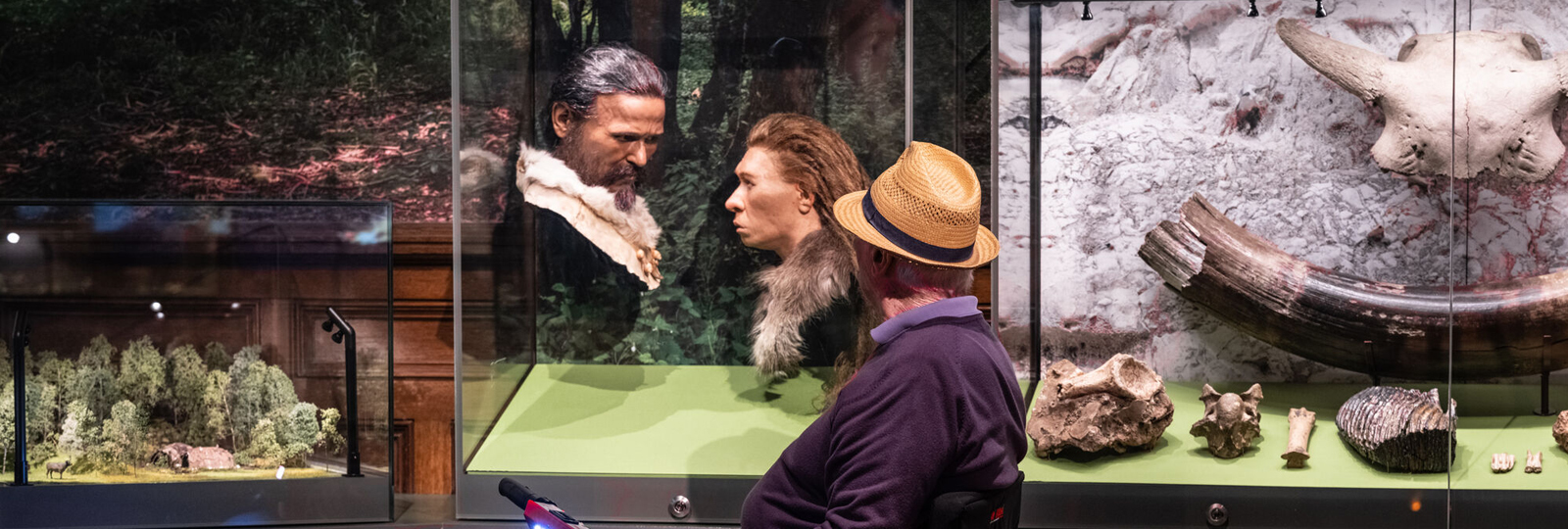 A man in a straw hat looks at the case of replica heads in the Archaeology Gallery of Brighton Museum