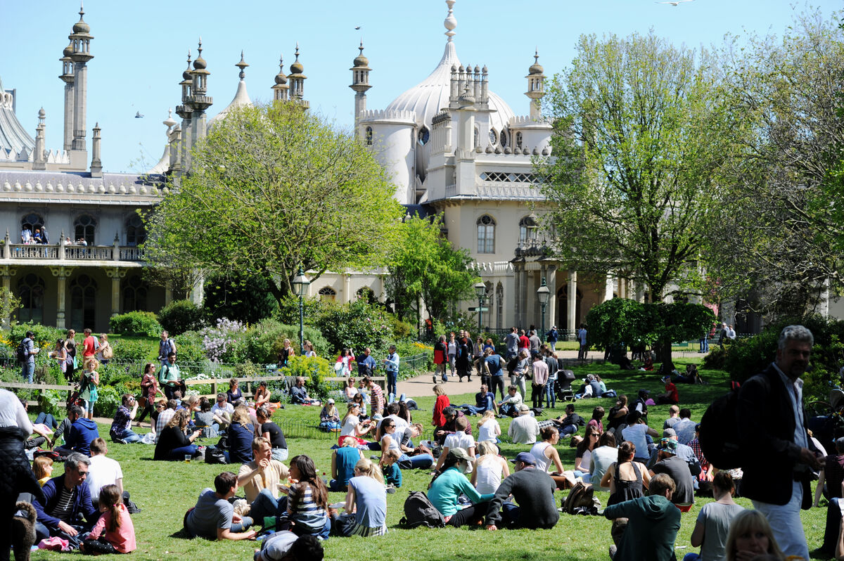 The Royal Pavilion Garden in the sunshine. Crowds on people are sitting on the lawn