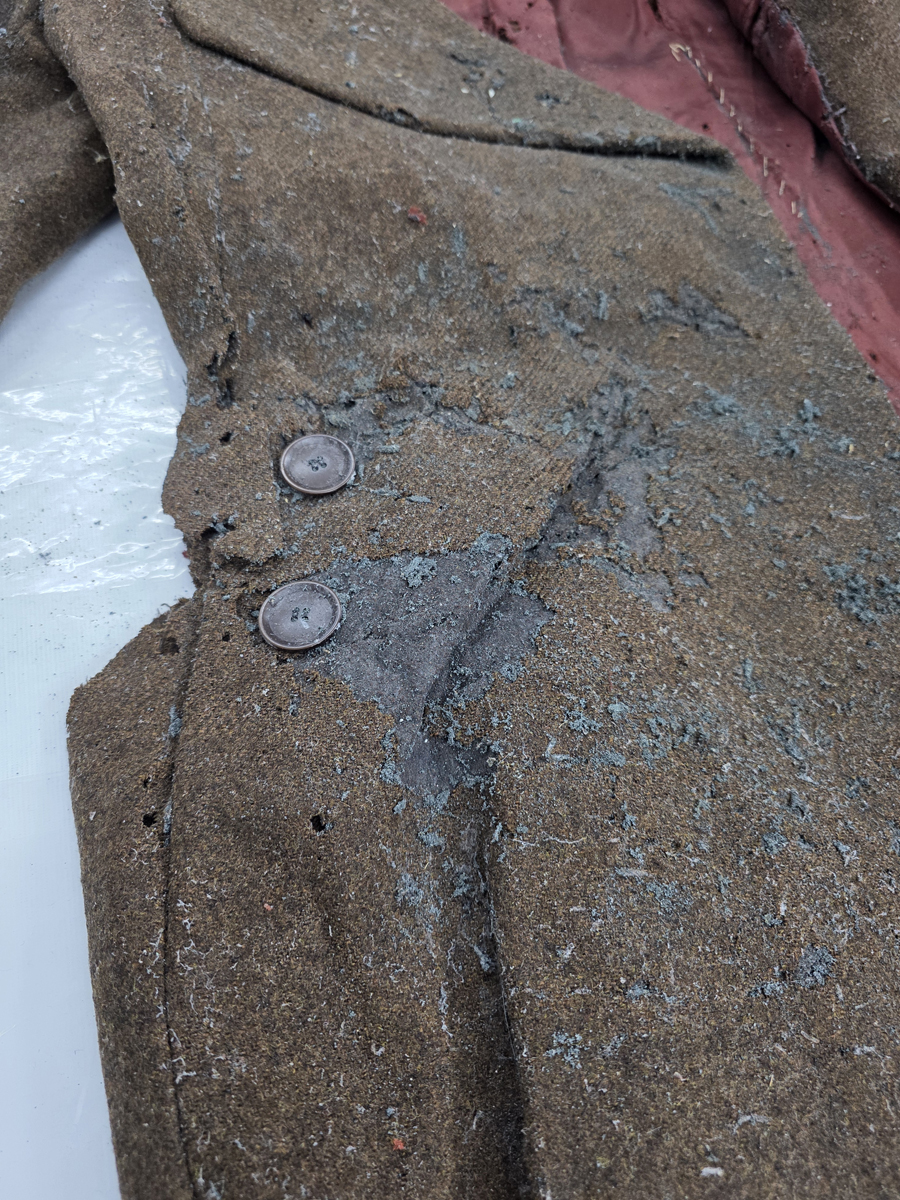 The coat with significant pest damage, now undergoing the disposal process