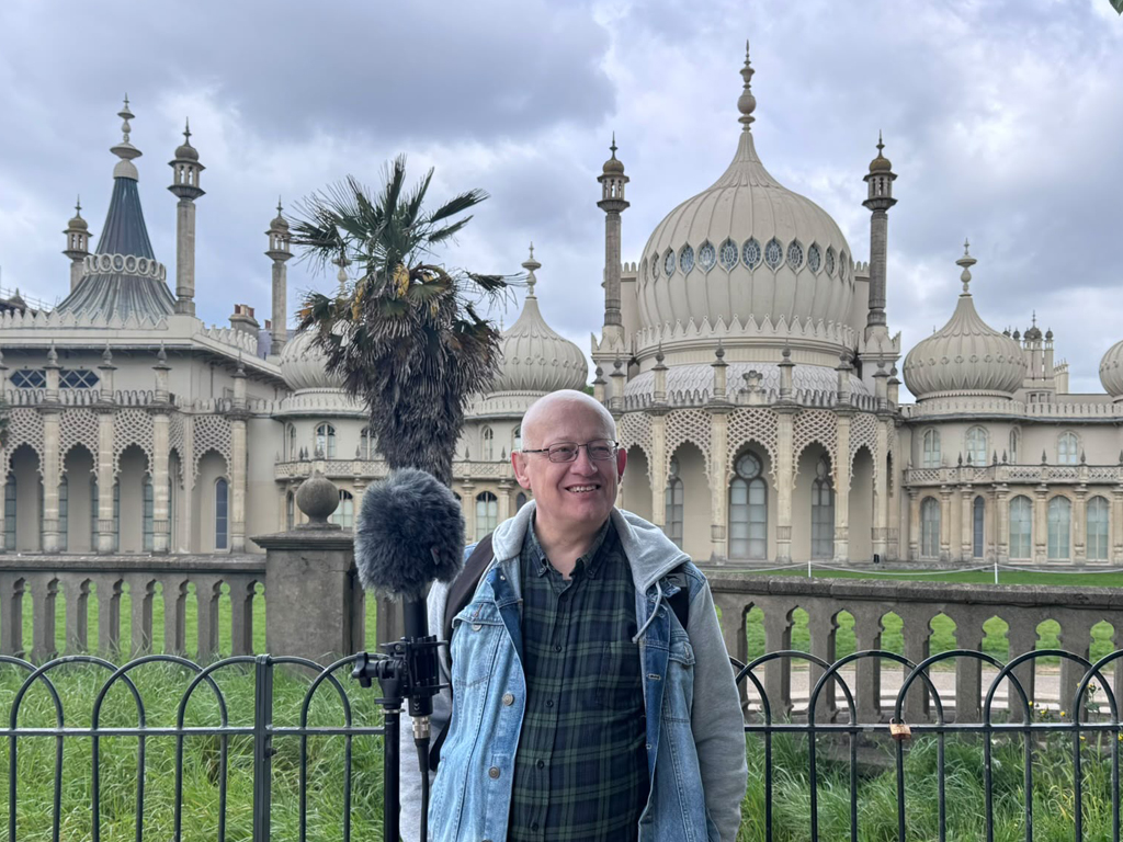 Peter Bourne elm garden audio tour. A man stands in the Royal Pavilion garden with a large microphone