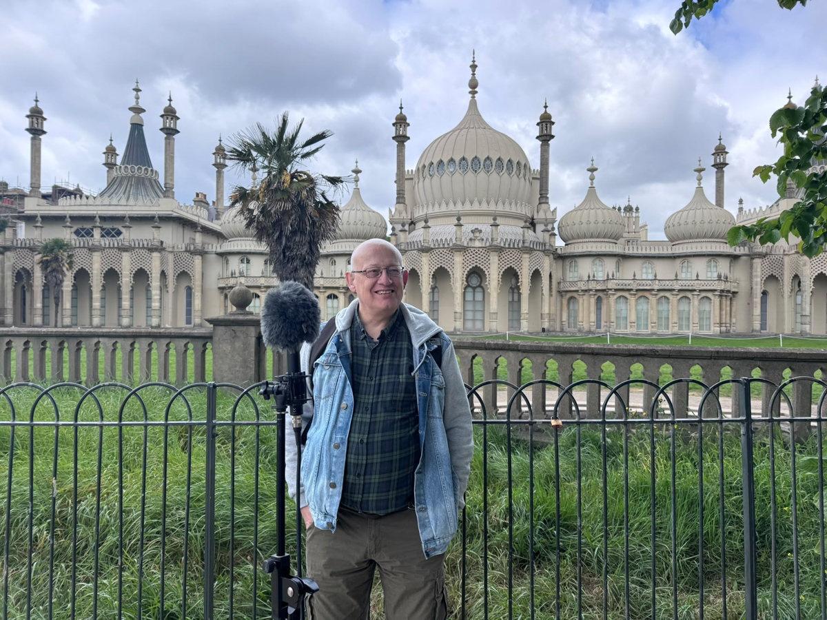 Peter Bourne elm garden audio tour. A man stands in the Royal Pavilion garden with a large microphone
