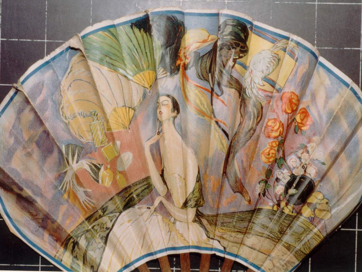 Advertising fan with paper leaf & wooden sticks & guards obverse: chromolitho woman with cascade of gloves, scent bottles, fans, hats reverse: scent bottle & foliate swags labelled: Royal Origan