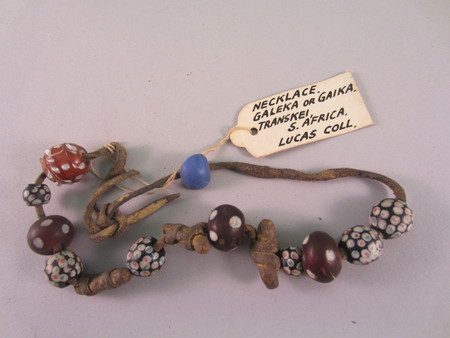 Necklace consisting of coloured beads and three pieces of wood strung on unknown textile. Collected in the Transkei, Cape Colony, South Africa. Worn by the Galekas people in Transkei, a historical administrative district.